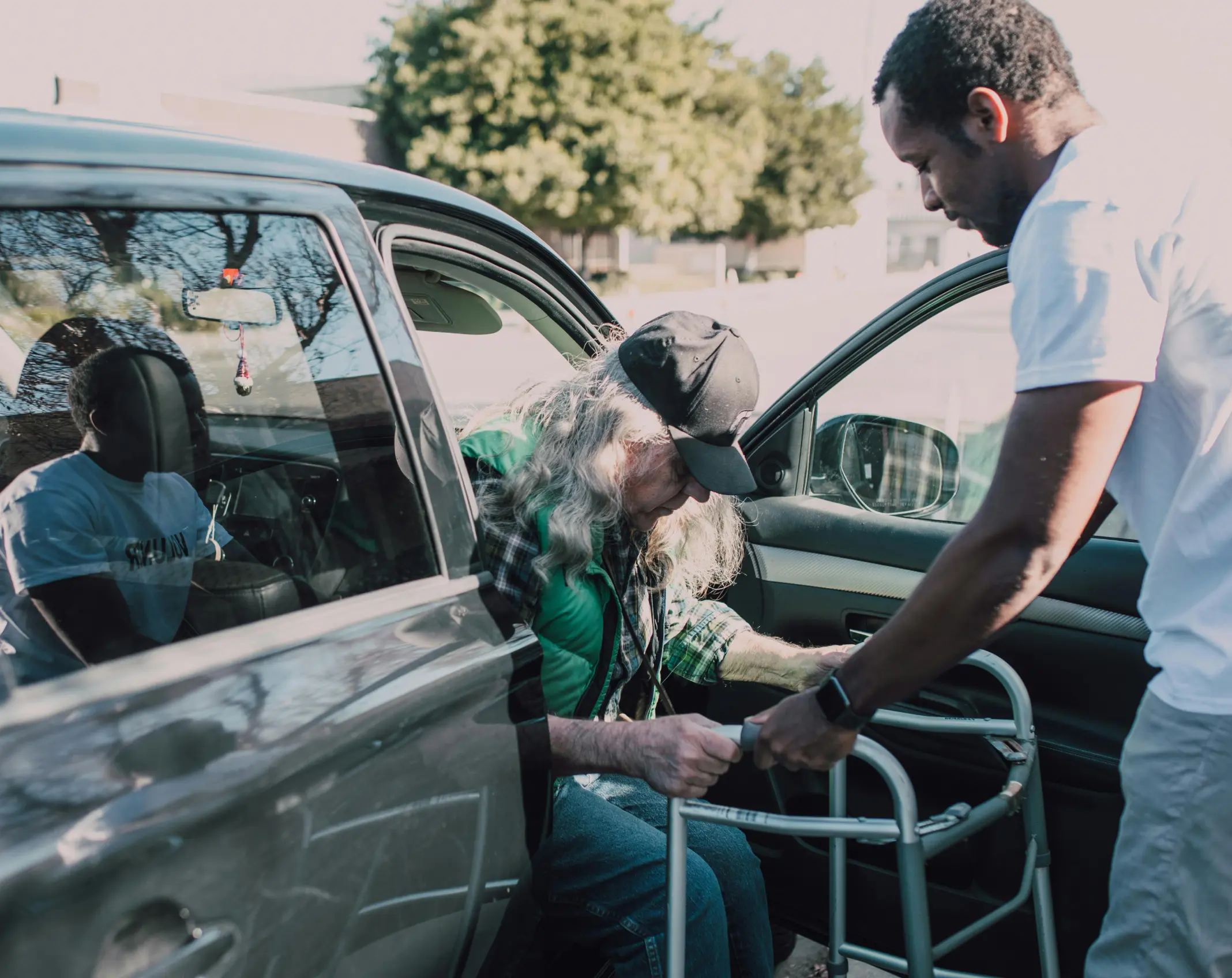 Man kindly helping an elderly woman get out of a car